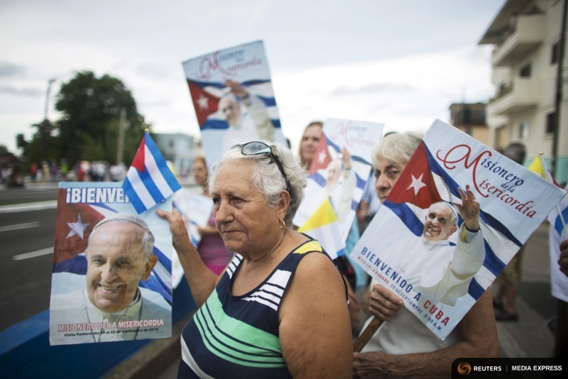 Teresa Fernandez Salgado holds a sign with an image of Pope Francis as she waits for his arrival from the airport in Havana