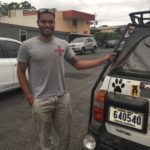 Staff member of Vida Volunteers holding onto his car