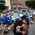 A softball team hugs after paying their respects at a makeshift memorial at Dallas Police Headquarters following the multiple police shootings in Dallas,