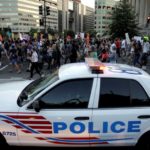 Demonstrators with Black Lives Matter march past a Metropolitan police officer blocking traffic during a protest in Washington