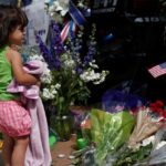 Abigail Garcia,2, visits a makeshift memorial at Dallas Police Headquarters two days after a lone gunman ambushed and killed five police officers at a protest decrying police shootings of black men, in Dallas, Texas