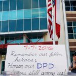 A woman stands by a makeshift memorial at Dallas Police Headquarters two days after a lone gunman ambushed and killed five police officers at a protest decrying police shootings of black men, in Dallas, Texas