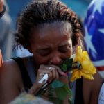 Victor Taylor supports Keaka Wallace, who says she was a patrol partner of slain DART officer Brent Thompson, weeps as she leaves a makeshift memorial at Dallas Police Headquarters following the multiple police shooting in Dallas