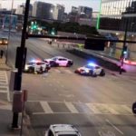 Police officers take cover behind their vehicles while under fire in downtown Dallas