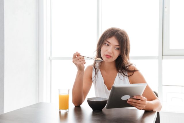 storyblocks/graphicstock-sad-bored-young-woman-eating-and-using-tablet-on-the-kitchen-at-home_H_eX64dL2g