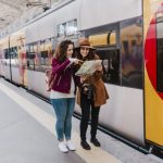 freepik/two women friends at train station waiting to take a train and t