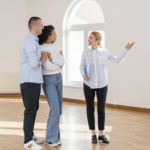 smiley-female-realtor-showing-empty-house-couple_23-2148895448