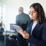 focused-office-lady-glasses-using-tablet-while-two-mature-businessmen-discussing-work-glass-wall-copy-space-communication-concept_74855-14243