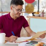 photo-young-inexperienced-entrepreneur-records-information-from-business-documents-notepad-studies-graphics-charts-gets-prepared-presenting-information-investors-drinks-coffee_273609-29632