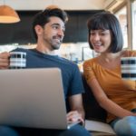 portrait-young-couple-spending-time-together-using-laptop-while-sitting-couch-home_58466-15537