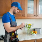 repairman-stands-kitchen-blue-cap-writes-tablet_353017-491