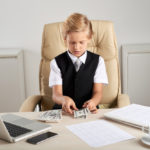 young-caucasian-boy-sitting-executive-chair-office-counting-dollars-desk_1098-20313