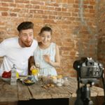 young-couple-cooking-recording-live-video-vlog-social-media_155003-22193