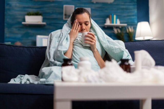 sick-woman-sitting-home-blanket-with-hot-tea