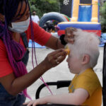 A volunteer paints Daniel’s face.