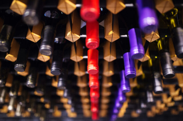 Various wine bottles in row on wooden shelf. Asset ID: SBI-305137745