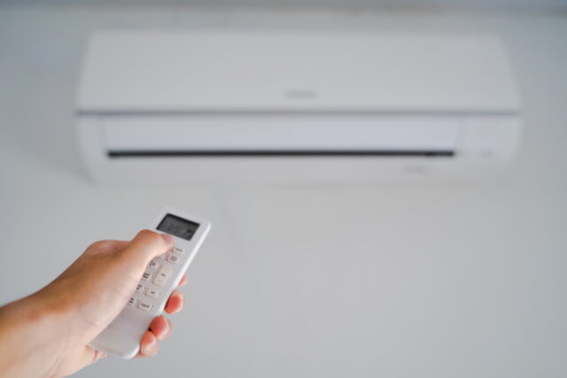 Man hand operating remote controller the air conditioner inside the room. https://www.vecteezy.com/photo/2910136-man-hand-operating-remote-controller-the-air-conditioner-inside-the-room