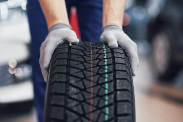 Closeup of mechanic hands pushing a black tire in the workshop. https://www.freepik.com/free-photo/closeup-mechanic-hands-pushing-black-tire-workshop_9122514.htm#query=tires&position=26&from_view=search