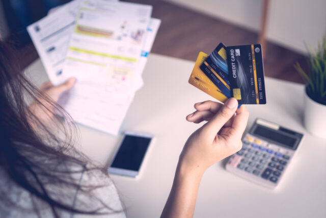 https://www.vecteezy.com/photo/2102186-close-up-woman-s-hand-holding-three-credit-cards-and-papers-at-a-desk-with-calculator-and-a-cell-phone