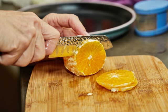 Chef cuts the orange into slices with knife. https://www.freepik.com/premium-photo/chef-cuts-orange-into-slices-with-knife-close-up_19755215.htm#query=peeling%20fruit&position=24&from_view=search&track=ais