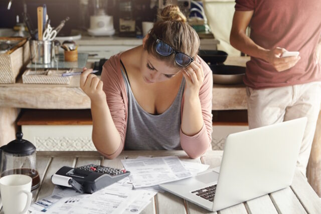 Financial troubles and economic crisis. Indoor shot of young casual housewife reviewing family finances, calculating expenses, making notes with pen, sitting at kitchen table with papers and laptop https://www.freepik.com/free-photo/financial-troubles-economic-crisis_9957104.htm#query=mortgage%20trouble&position=24&from_view=search&track=ais