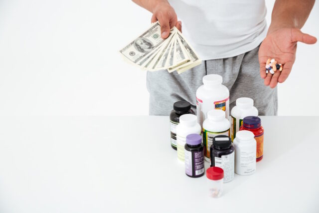 Cropped image of young sportsman holding vitamins and money. https://www.freepik.com/free-photo/cropped-image-young-sportsman-holding-vitamins-money_7836221.htm#query=costly%20drugs&position=14&from_view=search&track=ais
