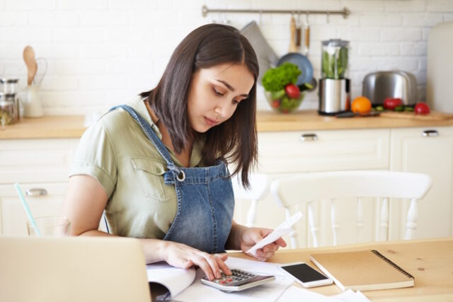 People, finance, home economics and modern technology concept. Portrait of beautiful young dark haired housewife calculating gas and electricity bills, sitting at table, using calculator and laptop https://www.freepik.com/free-photo/expressive-pretty-woman-posing_11199614.htm#query=doing%20taxes&position=16&from_view=search&track=ais