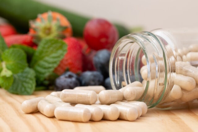 Viitamins supplements in the glass bottle on the wooden table wi https://www.freepik.com/premium-photo/viitamins-supplements-glass-bottle-wooden-table-with-variety-fruit_30361511.htm#query=vegan%20protein%20pills&position=18&from_view=search&track=ais