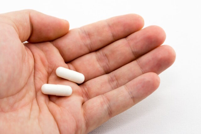 Closeup shot of a person holding two white capsules with a white background By Katharine Lang on May 31, 2023 — Fact checked by Patricia Weiser, PharmD