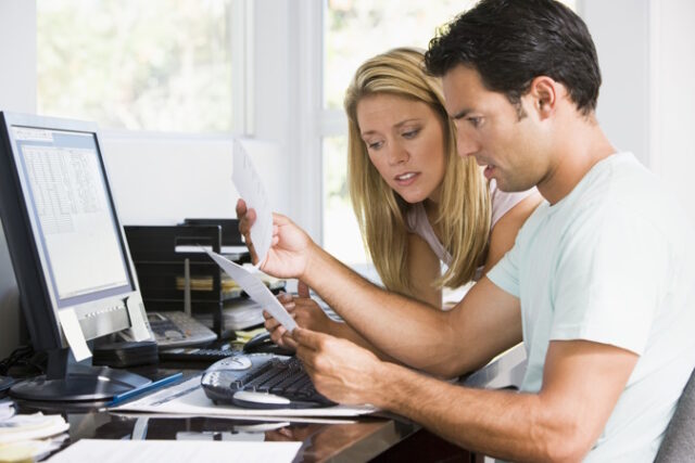 Couple in home office with computer and paperwork looking unhapp Asset ID: SBI-301053928