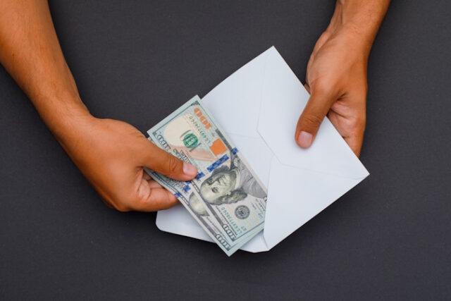 Financial concept on dark grey background flat lay. hands putting banknotes in envelope. https://www.freepik.com/free-photo/hands-putting-banknotes-envelope_8999461.htm#page=2&query=pay%20cash&position=13&from_view=search&track=country_rows_v1