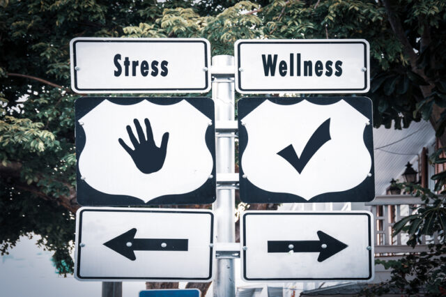 https://www.dreamstime.com/street-sign-to-wellness-versus-stress-direction-way-image155887371