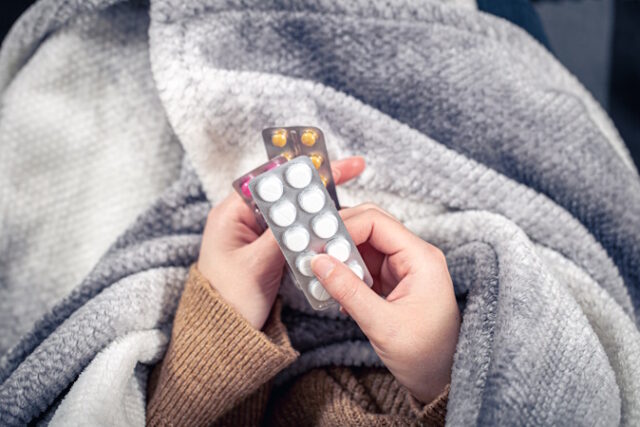 Close-up of pills in the hands of a sick woman, wrapped in a plaid, top view. https://www.freepik.com/premium-photo/closeup-pills-female-hands-top-view_21557176.htm#fromView=search&page=1&position=17&uuid=62dbba87-22f2-4f13-8a2d-d2e8f4938b02&query=cold+pills
