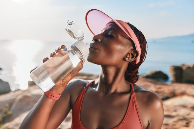 Woman drinking water from a bottle by the seaside against a sunny sky https://www.vecteezy.com/photo/51234207-a-fit-woman-in-a-cap-enjoying-water-from-a-bottle-with-a-serene-ocean-background-and-a-warm-sunny