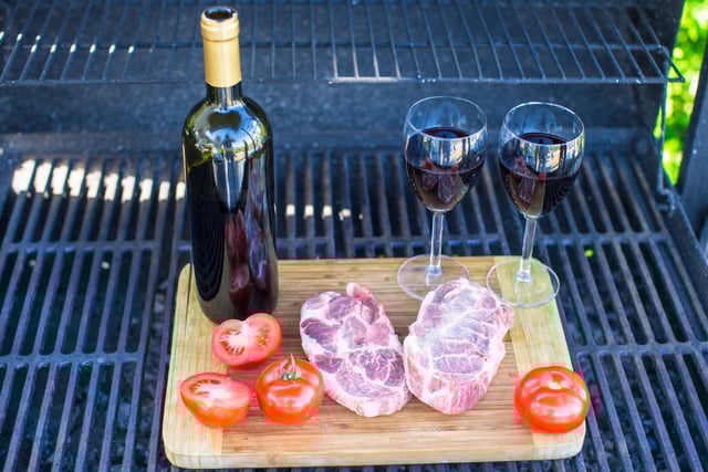 Two glass of red wine, steak and tomatoes on barbecue outdoors https://www.vecteezy.com/photo/18124300-two-glass-of-red-wine-steak-and-tomatoes-on-barbecue-outdoors