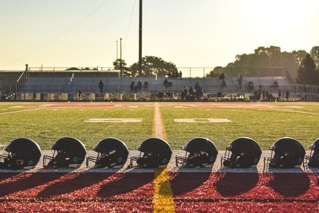 dani-adkins-civXaE08gKE-unsplash https://unsplash.com/photos/a-group-of-football-helmets-sitting-on-top-of-a-field-civXaE08gKE