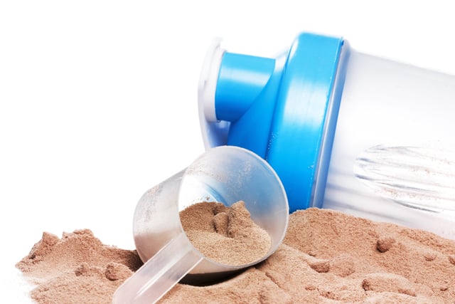 Shaker, scoop and chocolate whey protein or mass gainer powder https://www.vecteezy.com/photo/16288764-shaker-scoop-and-chocolate-whey-protein-or-mass-gainer-powder