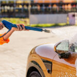 Close up pressure washer spraying foam on car at self service car wash