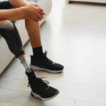 Closeup of unrecognizable man with bionic prosthetic leg at home indoors, copy space