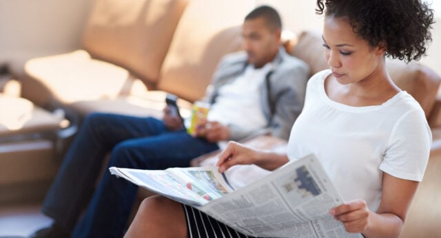 woman-reading-newspaper-sofa-article-information-knowledge-stock-market-living-room-print-update-person-with-man-publication-newsletter-trending-story-home person reading newspaper