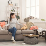 Desperate woman sitting on sofa in messy room