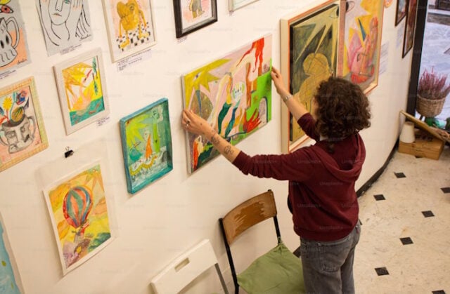 https://unsplash.com/photos/a-woman-hangs-paintings-on-a-gallery-wall-c0segOndxpE