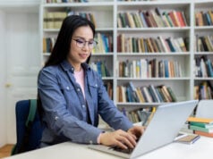 https://www.vecteezy.com/photo/68905002-a-woman-with-glasses-using-a-laptop-in-a-library-with-bookshelves-in-the-background-she-is-studying