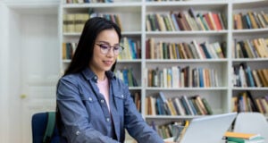 How Much Should You Budget for an Online LMS Course Platform? https://www.vecteezy.com/photo/68905002-a-woman-with-glasses-using-a-laptop-in-a-library-with-bookshelves-in-the-background-she-is-studying