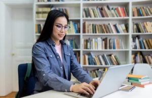 How Much Should You Budget for an Online LMS Course Platform? https://www.vecteezy.com/photo/68905002-a-woman-with-glasses-using-a-laptop-in-a-library-with-bookshelves-in-the-background-she-is-studying