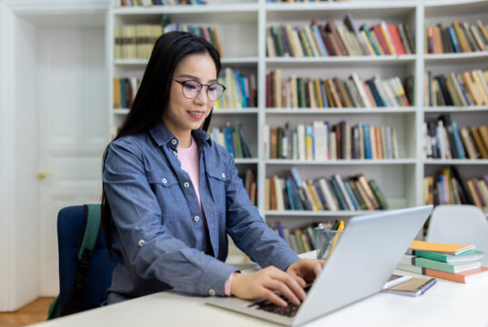 https://www.vecteezy.com/photo/68905002-a-woman-with-glasses-using-a-laptop-in-a-library-with-bookshelves-in-the-background-she-is-studying