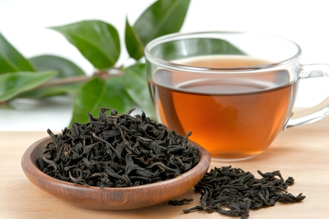 Dried tea leaves resting in small wooden bowl near cup of tea https://www.vecteezy.com/photo/59892440-dried-tea-leaves-resting-in-small-wooden-bowl-near-cup-of-tea